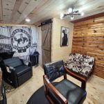 Hair saloon with black chairs and wood paneling.